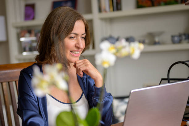 istock Woman reading or watching media on her laptop computer 1317558431