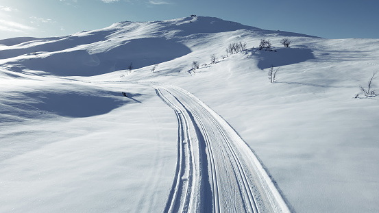 Cross country skiing slope running though stunning snow covered mountain terrain on a cold sunny winters day,.