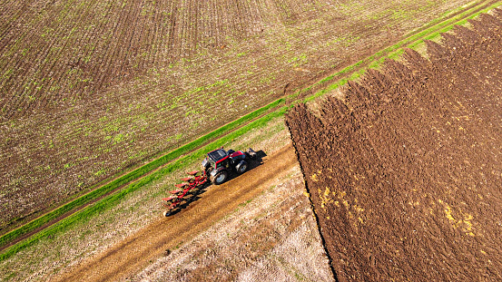 A drone view of a tractor working the land in the field in autumn