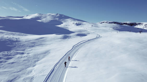 active couple cross country skiing on a slope through wild snowy mountain wilderness. - nordic event fotos imagens e fotografias de stock