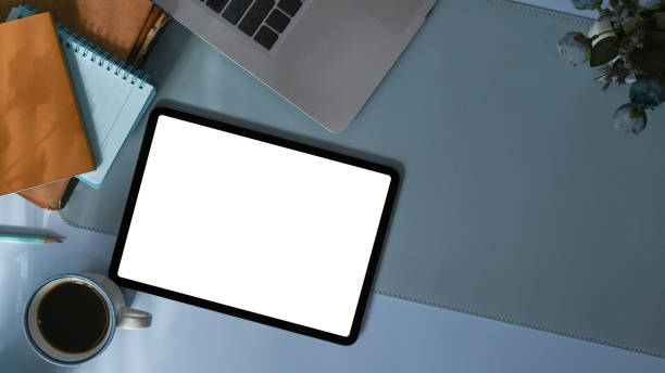 istock Top view modern workspace with digital tablet, laptop, coffee cup and notebook on blue leather. 1317561171