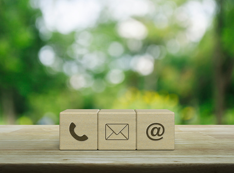 Telephone, mail, email address icon on wood block cubes on wooden table over blur green tree in park, Business customer service and support online concept