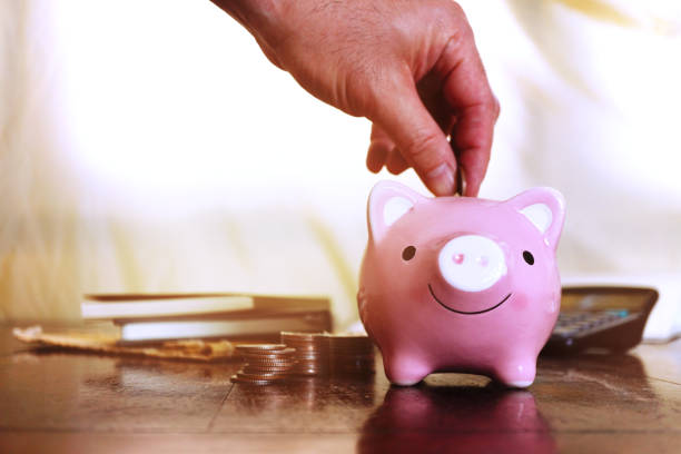 istock Hand fill coin in pink pig saving with background coins stack and calculator , banking concept. 1317564829