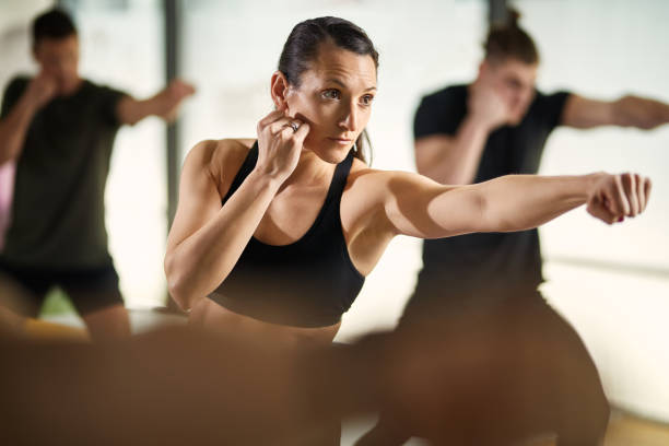 athletische frau im kampf haltung üben kampfkünste im health club. - verteidigen stock-fotos und bilder