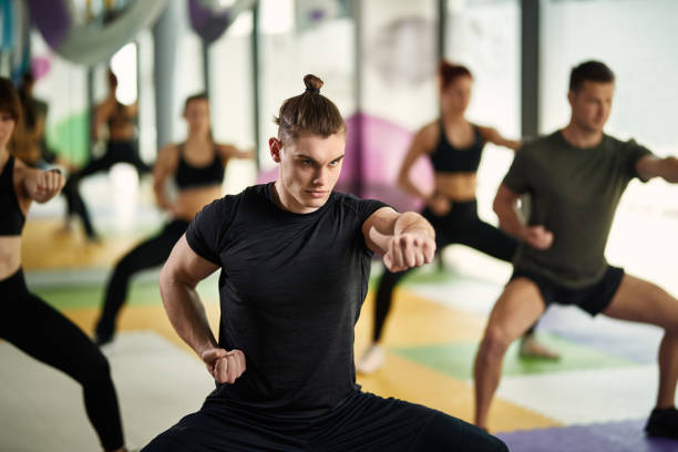 istock Dedicated athlete practicing martial arts while working out with group of people at health club. 1317564874