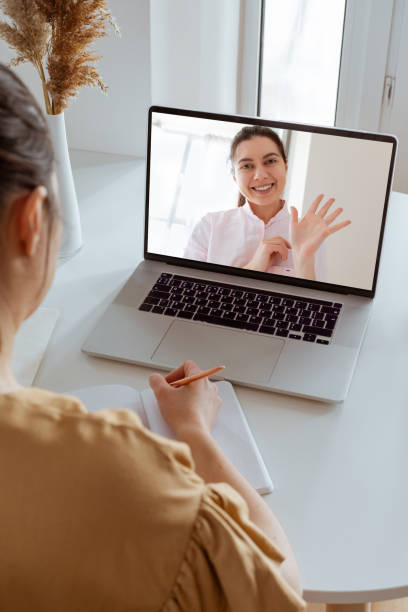 Back view and close up of with non-caucasian woman making video call in modern home interior. Diverse workers or friends chatting online, web conference, consulting client. Back view and close up of with non-caucasian woman making video call in modern home interior. Diverse workers or friends chatting online, web conference, consulting client. zoom classroom stock pictures, royalty-free photos & images