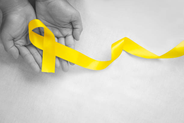 istock Hand holding Yellow ribbon on white background, copy space. Bone cancer, Sarcoma Awareness, childhood cancer, cholangiocarcinoma, gallbladder cancer, world Suicide Prevention Day. Health concept. 1317568199
