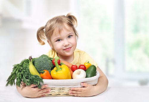 Child holding basket of fresh fruits and vegetables.Kid's healthy nutrition. Eco fresh grown food concept.Organic food.