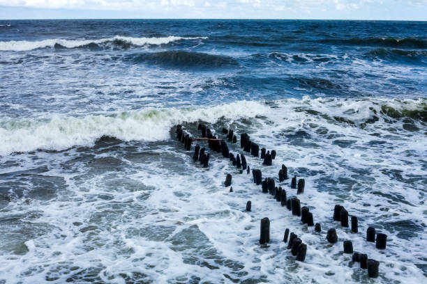 Beautiful sharp stones on the seashore, washed by the waves. Stone ridges on a wild beach. Smooth and long stone formations going into the sea. Beautiful photo of marine nature.