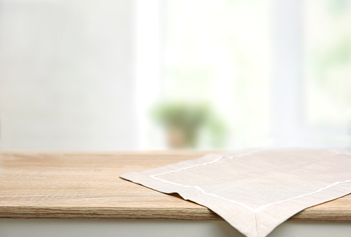 Empty space table decorated with beige towel food advertisement display. Tabletop with advertisement place. Blurred kitchen backdrop. Food promotion background.