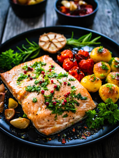 bistecche di salmone fritto, patate bollite e verdure fresche su sfondo di legno - salmone arrosto foto e immagini stock