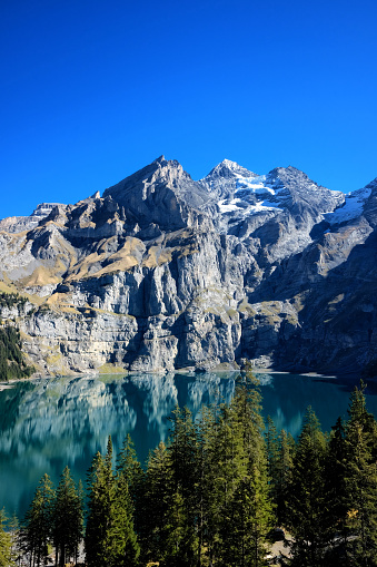 Oeschinensee lake in Kandersteg, Switzerland. Panoramic view of the mountains and azure water on a clear sunny summer day. Popular tourist attraction.