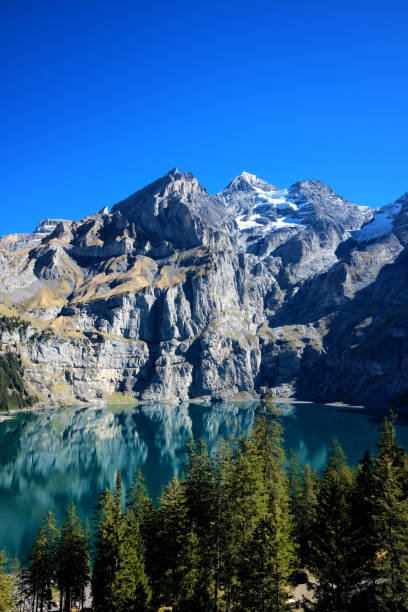 Panoramic view of Oeschinensee lake in Switzerland. Oeschinensee lake in Kandersteg, Switzerland. Panoramic view of the mountains and azure water on a clear sunny summer day. Popular tourist attraction. lake oeschinensee stock pictures, royalty-free photos & images