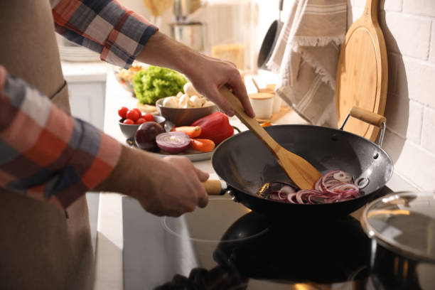 istock Man stirring onion slices in frying pan, closeup 1317580972