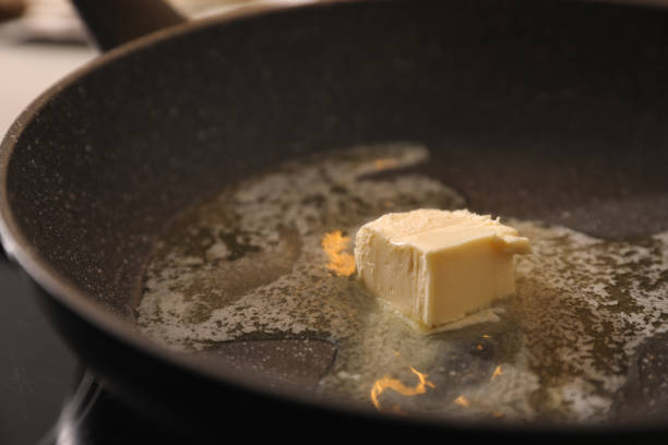 Frying pan with melted butter on stove, closeup