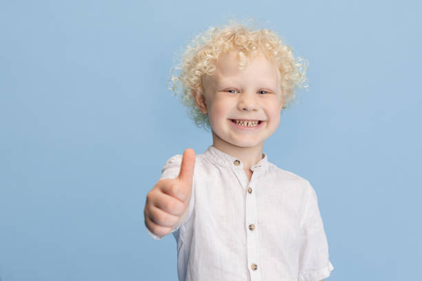 Portrait of happy smiling boy posing isolated over blue studio background.