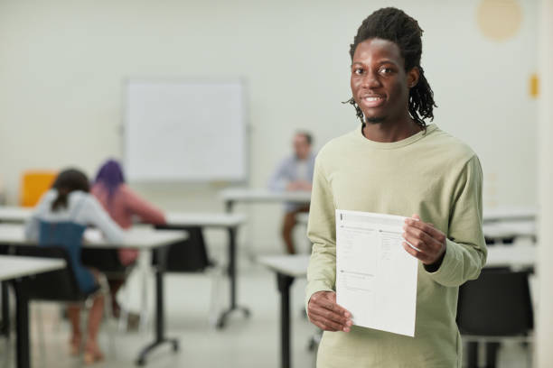 istock Young man holding test certificate in school 1317585001