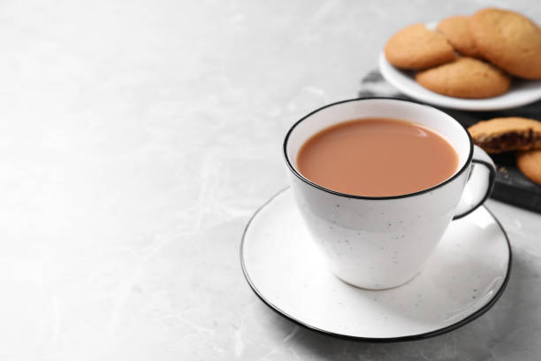 istock Delicious tea with milk in white cup near cookies on grey table. Space for text 1317587841