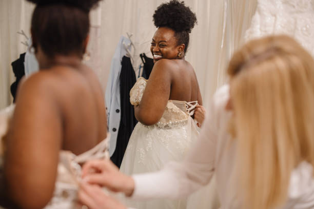 istock Shop assistant helping bride get into wedding dress 1317588088