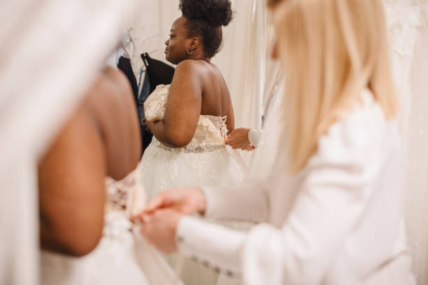 istock Shop assistant helping bride get into wedding dress 1317588215