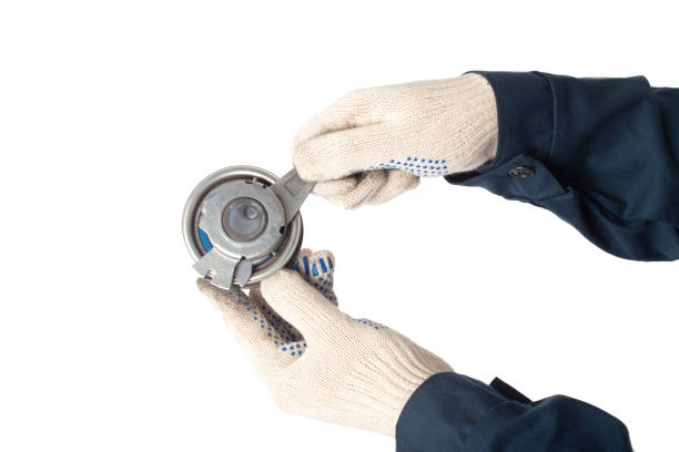 istock A car locksmith holds a spent old timing belt tensioner roller on a white background, isolate. Timing Belt Roller Replacement Concept 1317589359