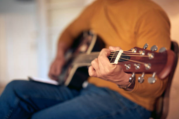 male musician playing acoustic guitar on the amplifier in retro vintage room. - fingerstyle imagens e fotografias de stock