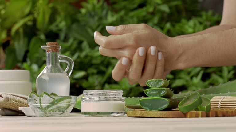 Panning shot of young woman moisturizing hands with aloe vera natural gel