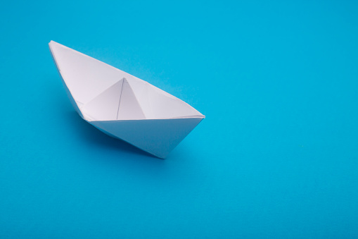 Above shot of white paper boat on blue background