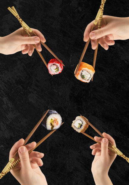 istock Women's hands hold sushi rolls with sticks. Black background. Creative concept. 1317596307