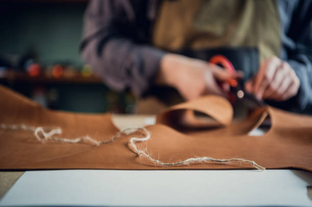 istock In a boot shop, an experienced young master cuts out leather shoe elements with scissors 1317599838