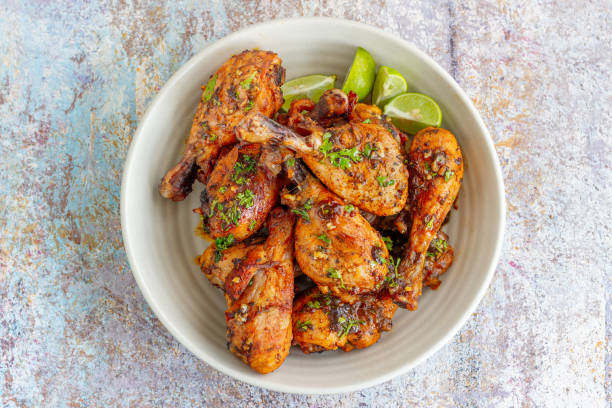 baquetas de pollo al horno en un tazón adornado con cilantro y limón - barbecue chicken fotografías e imágenes de stock