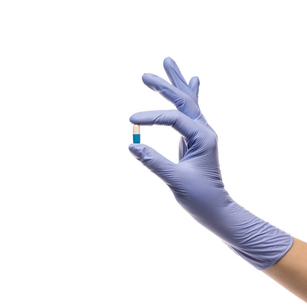 istock Hand in latex glove with a pill in a capsule on a white background 1317601933
