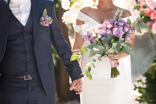 Boda ramo púrpura asimétrico en manos de la novia. photo
