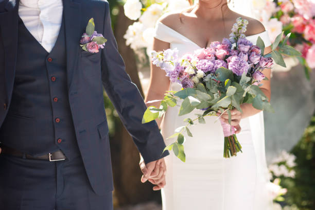 het asymmetrische purpere boeket van het huwelijk in de handen van de bruid. - wedding stockfoto's en -beelden