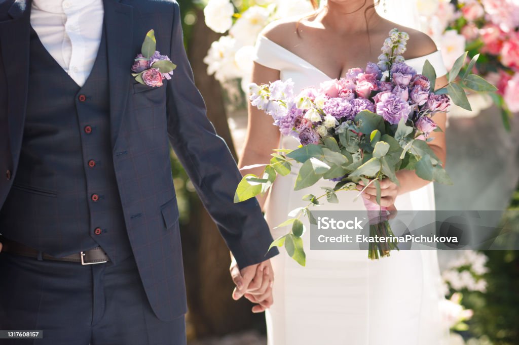 Wedding asymmetrical purple bouquet in the hands of the bride. Wedding purple bouquet in the hands of the bride. Wedding Stock Photo