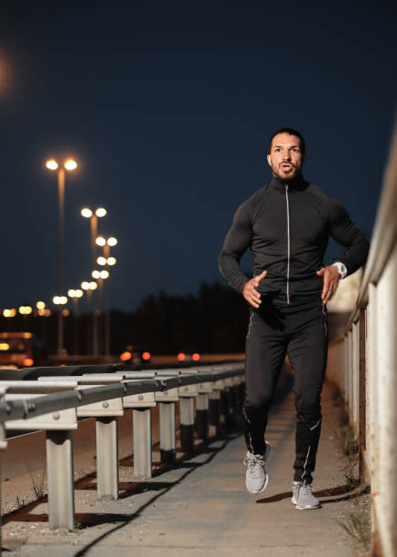 istock A young male athlete jogs at night. 1317608201