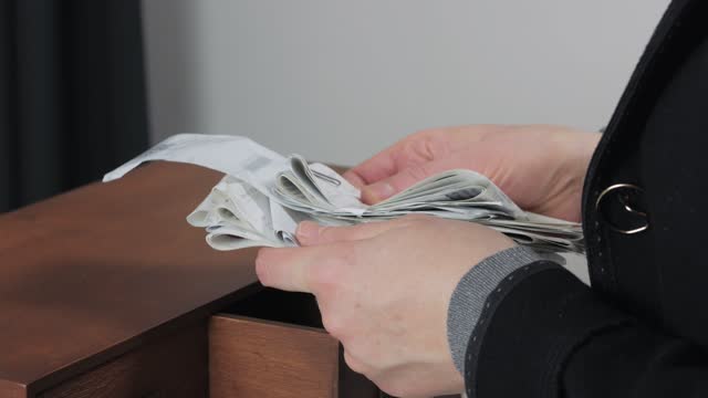 Close-up of a woman's hands with cash paper receipts from stores