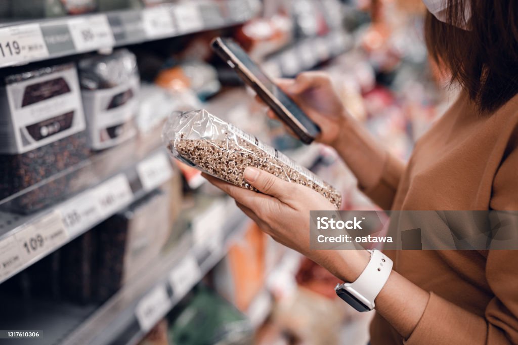 Woman shopping in supermarket and reading product information. Costumer buying food at the market. Closeup - Woman shopping in supermarket and reading product information. Costumer buying food at the market. Supermarket Stock Photo