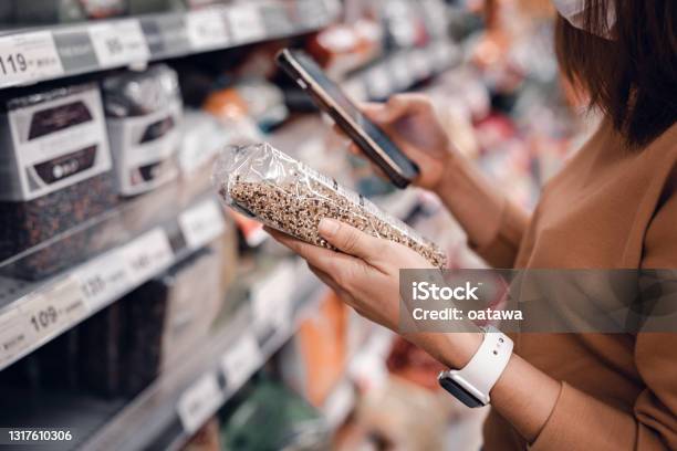 Woman Shopping In Supermarket And Reading Product Information Costumer Buying Food At The Market Stock Photo - Download Image Now