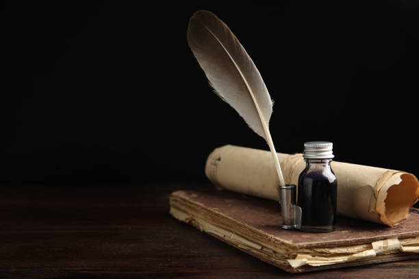 istock Feather pen, bottle of ink, old book and parchment scroll on wooden table. Space for text 1317611246