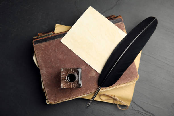 istock Feather pen, inkwell and old books on black table, top view 1317612988