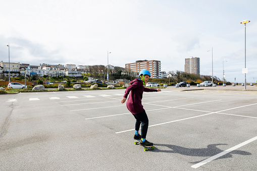 Mid age woman skateboarding in a parking lot in Liverpool in the North of England.