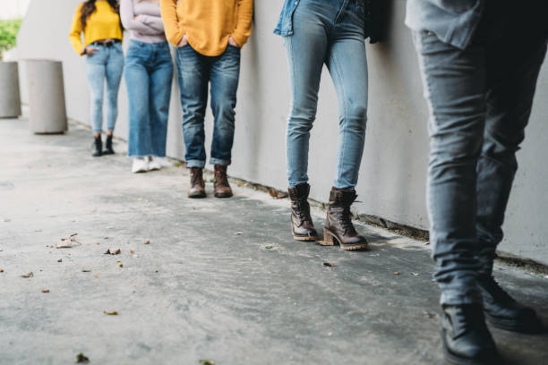 Low section view of people waiting in line in front of a store Low section view of people waiting in line in front of a store. They are standing against a wall. waiting in line stock pictures, royalty-free photos & images