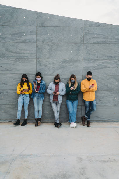 istock Friends are using a smart phone against a wall outdoor 1317614967