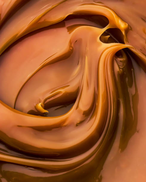 Caramel waves - close-up of golden details Caramel spread that looks like golden waves. Macro vertical capture, movement, strong soft shadows. Dark orange colour. caramel stock pictures, royalty-free photos & images