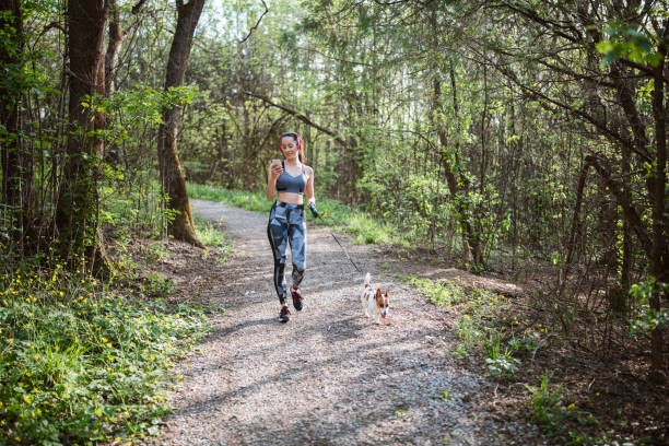 istock Young woman using her phone while walking in the forest with her dog. 1317617640