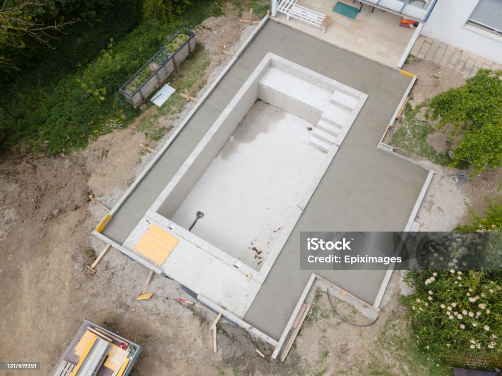 aerial drone flight pic of Swimming pool construction site from above aerial drone flight pic of Swimming pool construction site from above in a garden in austria Swimming Pool Stock Photo