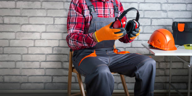 Man worker in uniform putting protective headphones. Construction safety. Banner.