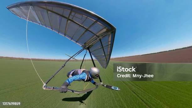 Hang Glider Pilot Approaches Landing On The Green Grassy Field Extreme Sport Stock Photo - Download Image Now