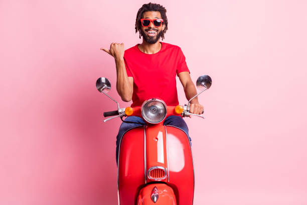 istock Portrait of handsome cheery guy riding moped showing copy empty blank space ad isolated over pink pastel color background 1317620557